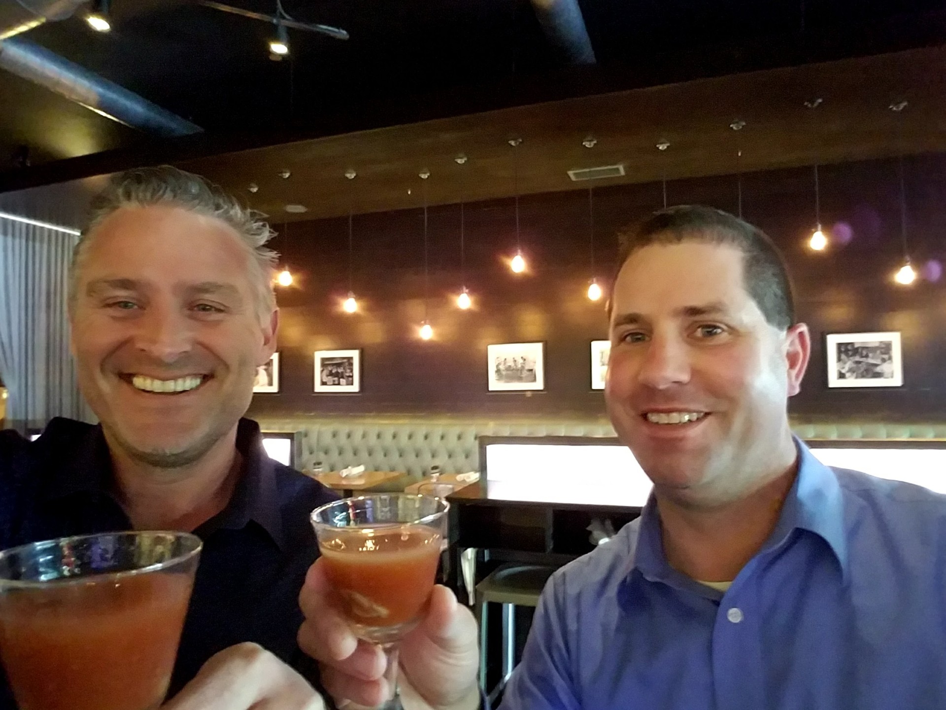 Todd and Russ raising Bloody Mary cocktails together at a happy hour oyster bar